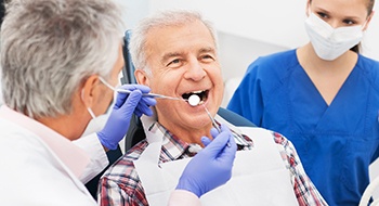 elderly man getting his teeth examined by his dentist 