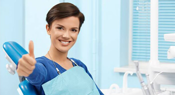 Smiling woman in dental chair giving thumb up