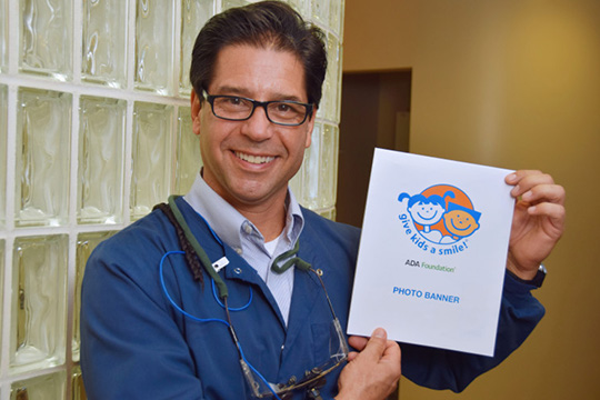 Dr. Lloyd holding a Give Kids a Smile flyer