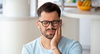 Man with black glasses experiencing toothache