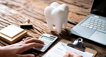 Patient calculating cost on desk with laptop