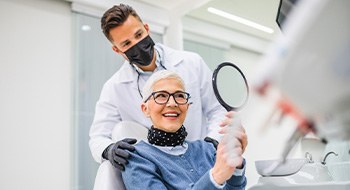 Woman smiling at reflection in handheld mirror