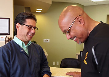 Man laughing with his Daytona Beach dentist at reception desk