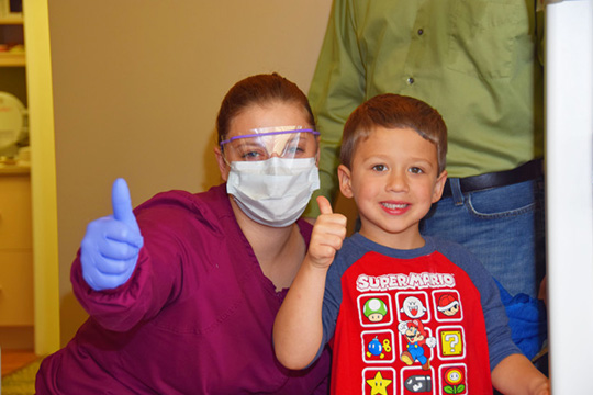 Team member and young boy giving thumbs up