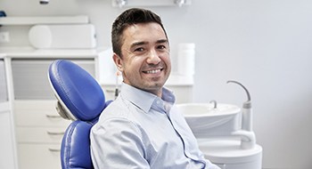 Hombre de camisa azul sonriendo en sillón dental