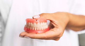 Dentist holding full dentures in Daytona Beach
