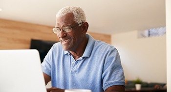 a person smiling and researching denture on a laptop