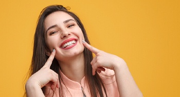 Woman pointing to her smile with yellow background