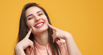 Woman pointing to her smile with yellow background