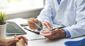 A dentist holds a mouth mold and talks to a patient about their available options for dental implant salvage in Daytona Beach