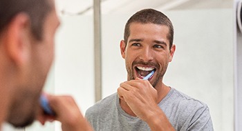 Man with dental implants in Daytona Beach brushing his teeth.