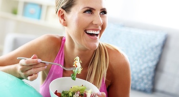 A young woman eats a salad after having a customized dental implant put into place in Daytona Beach