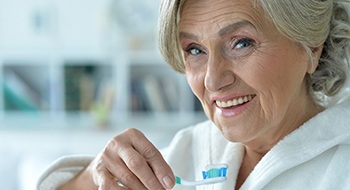 An older man wearing glasses and smiling after receiving dental implants in Daytona Beach