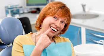 older woman pointing to her smile 