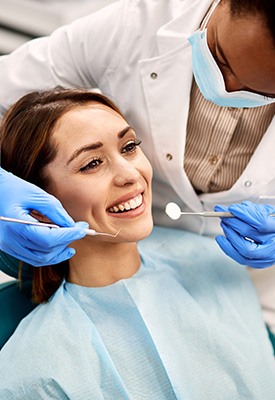 Dentist in blue gloves about to examine woman’s teeth