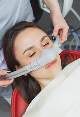 Dentist placing nitrous oxide mask over patient’s nose
