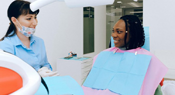 Woman in dental chair speaking with dentist