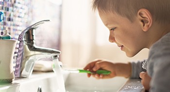 Little boy holding toothbrush under water