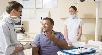 Man in dental chair talking to dentist