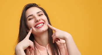 Woman pointing to her teeth after a smile makeover in Daytona Beach, FL