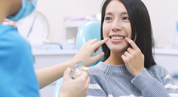 Woman pointing to her teeth at dentist.