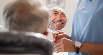 Man with veneers in Daytona Beach smiling in dentist's mirror