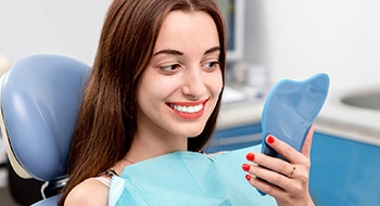 Young woman examining her smile in mirror