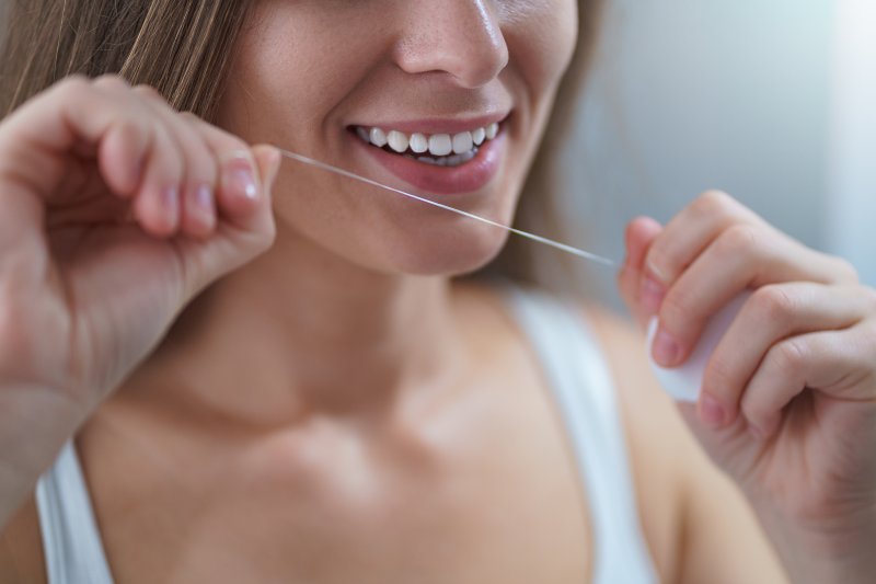 a young woman preparing to floss her teeth before bed