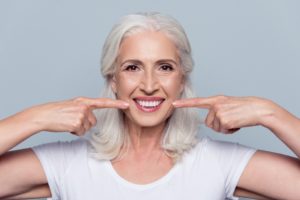 Older woman pointing to the cosmetic benefits of dental implants in Daytona Beach. 