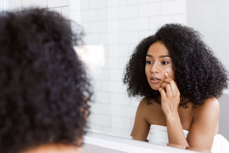 Woman examining her face in bathroom mirror