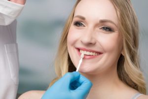 using shade guide at woman’s mouth to check veneer