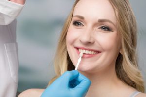 using shade guide at woman’s mouth to check veneer 