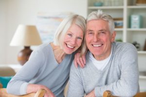 senior man and woman wearing matching gray cardigans