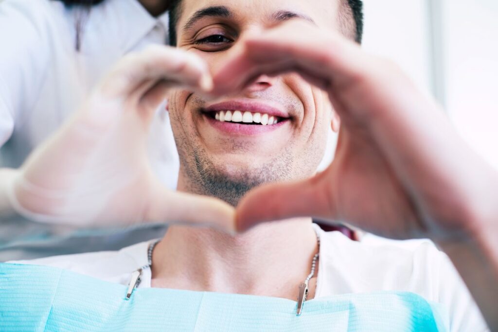 A man making a heart shape with his hands at the dentist’s office